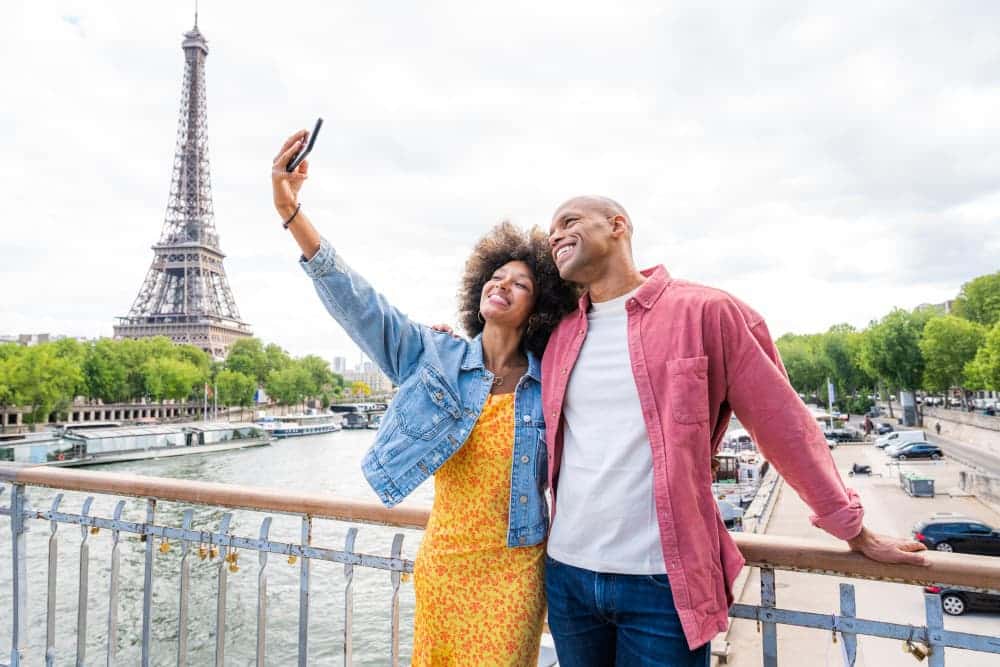 happy couple taking a selfie next to the Eiffel Tower during their vacation
