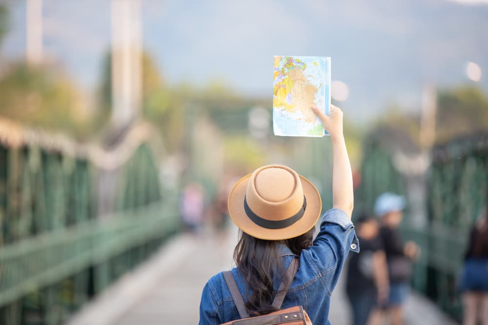 woman tourist crossing a bridge with a map on her hands